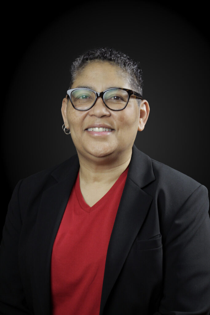 Headshot of Dr. Garcia Merchant with a black backdrop. Merchant is wearing a red shirt and black jacket.